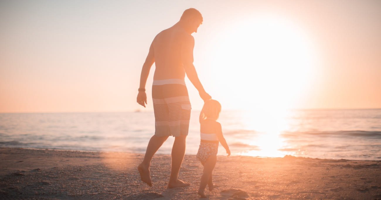 dad and son walking on the beach together at sunset