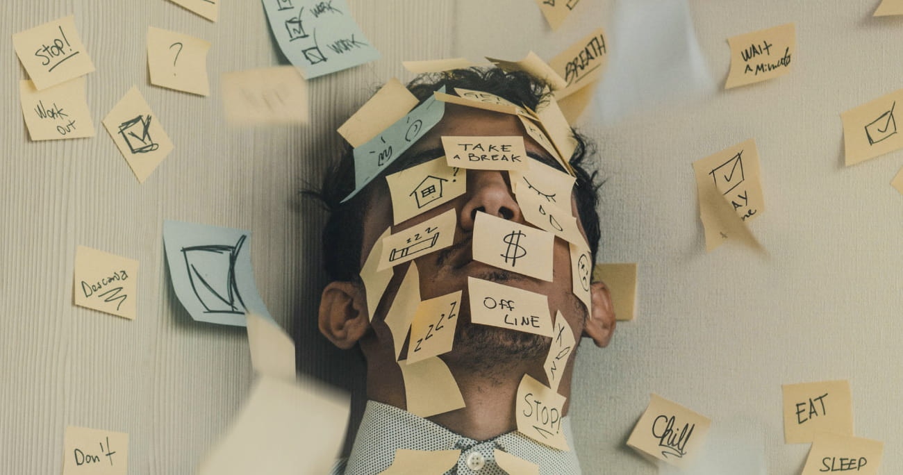 Man leaning against a wall with sticky notes all over his face